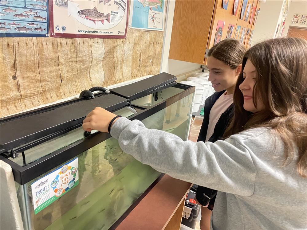 IMS students Lily & Brianna feed trout.